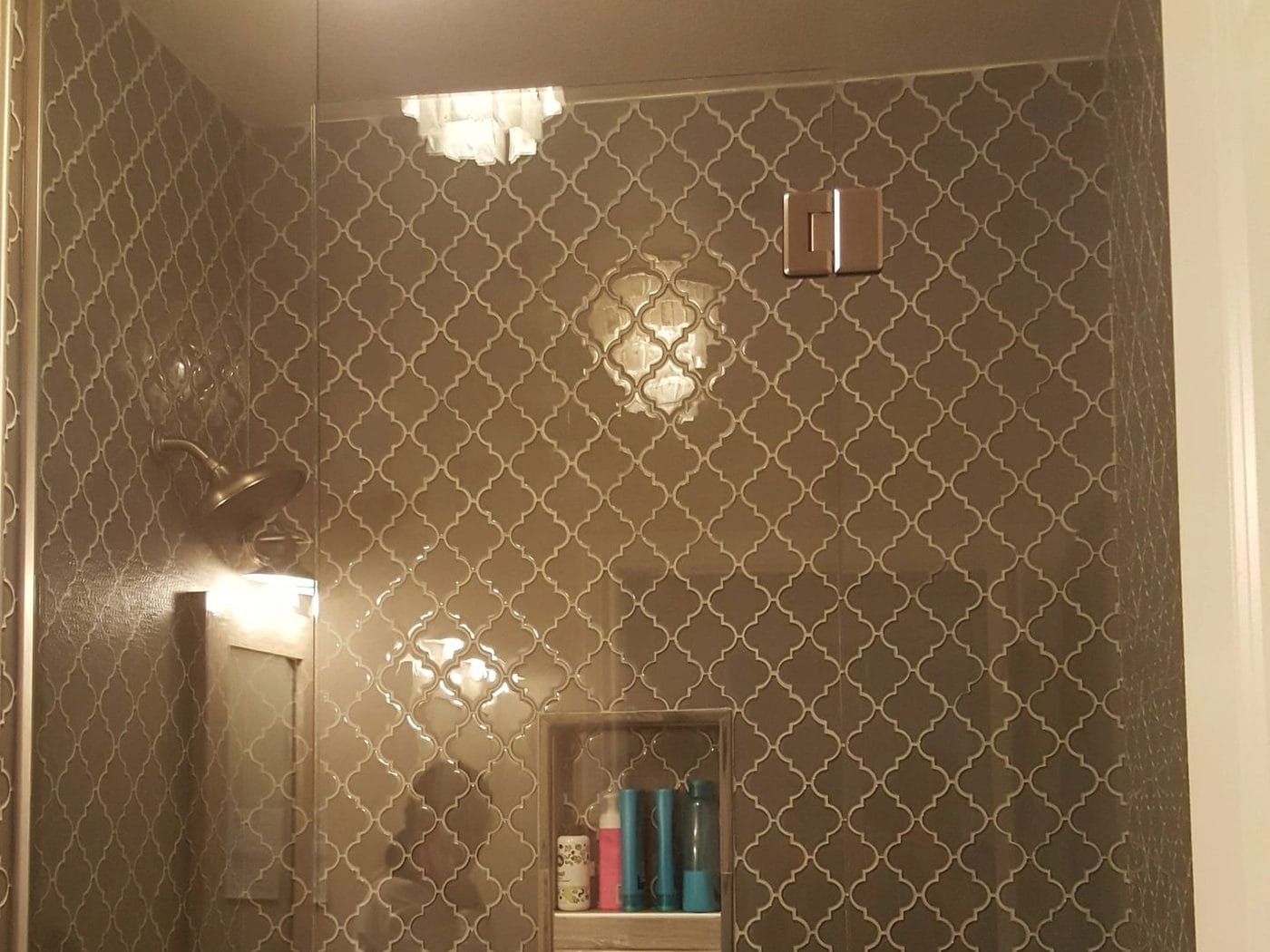 A tiled shower with a built-in niche and a wall light