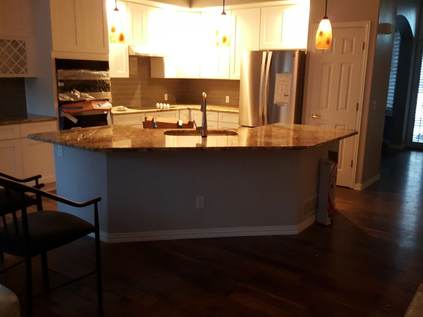 A kitchen island with pendant lighting and a granite top