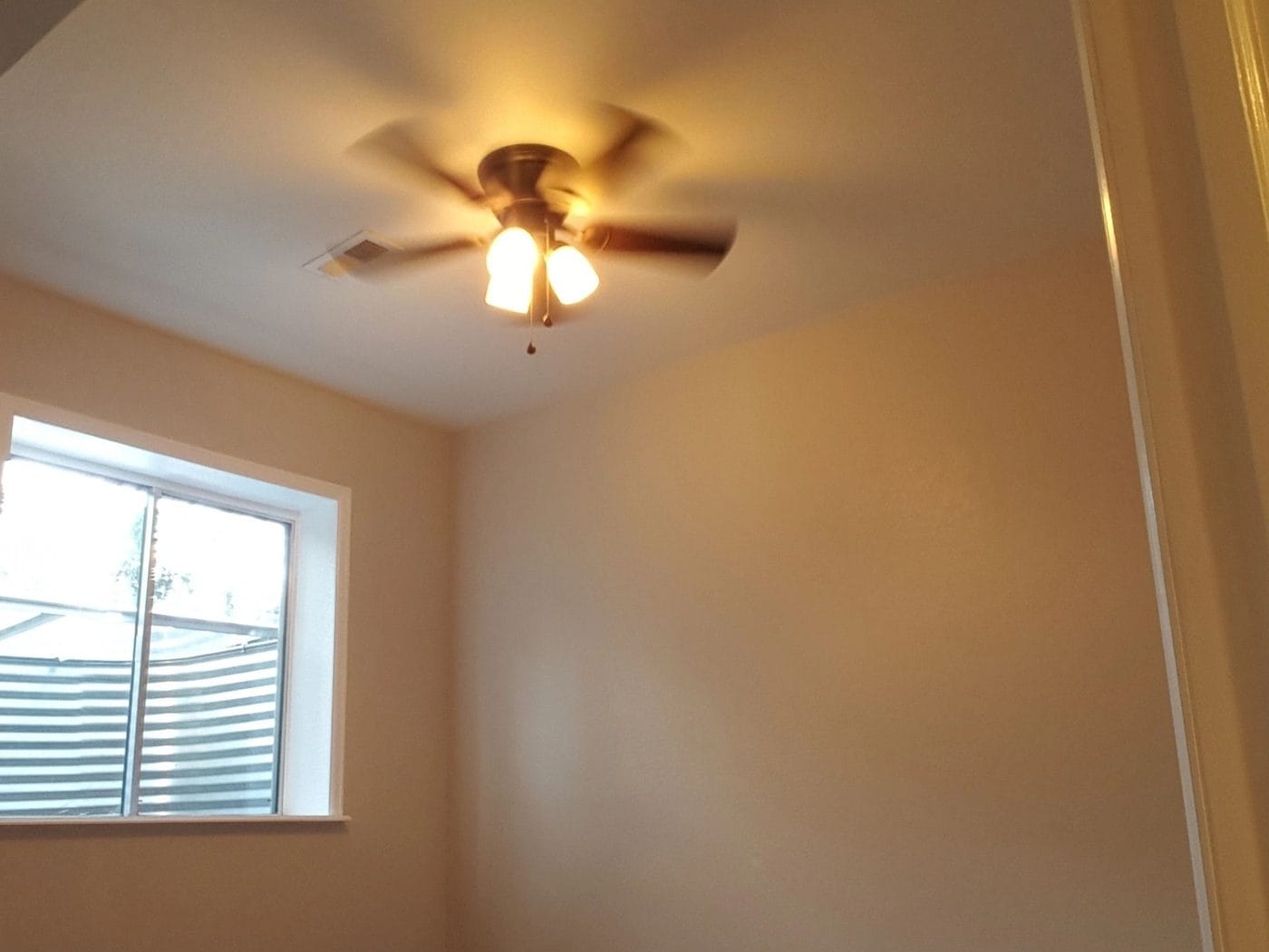 A finished basement room with a new window and a ceiling fan